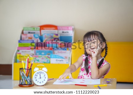 Portrait of little girl is sitting at the table and paints