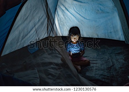 Ein mit einer Laterne beleuchteter Junge erzählt einem überraschten Mädchen im dunklen Wohnzimmer eine Gruselgeschichte