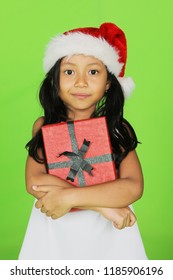 Portrait Of Little Girl Wearing Santa Hat While Holding Christmas Gift. Shot With Green Screen