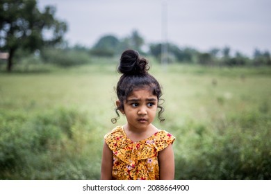 Portrait Of A Little Girl Wearing Yellow Jump Suit With A Bun On Her Head