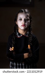 Portrait Of Little Girl With Wednesday Addams Costume During Halloween. Serious Expression And Dark Atmosphere With Dark Background