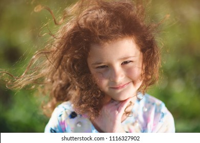 Portrait Of Little Pretty Caucasian Girl With Curly Hair Blown By Summer Warm Wind