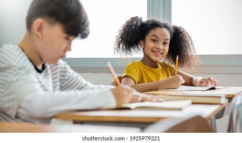 Portrait Of Little Pupil Writing At Desk In Classroom At The Elementary School. Student African Girl Doing Test In Primary School. Children Writing Notes In Classroom. Education Knowledge Banner