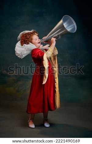 Portrait of little red-headed girl, child in costume of royal person shouting in megaphone isolated on dark green background. Concept of historical remake, comparison of eras, medieval fashion, queen