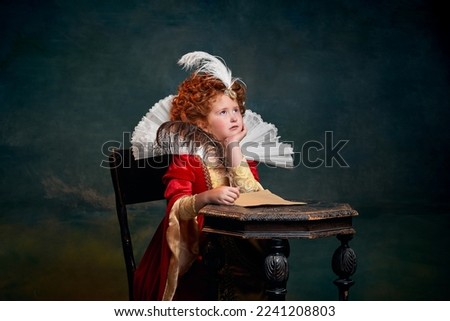 Portrait of little red-headed girl in costume of royal person writing letter with thoughtful look over dark green background. Concept of historical remake, comparison of eras, medieval fashion, queen