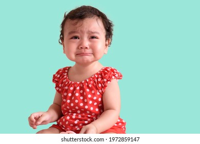 Portrait Of A Little Sadly Asian Baby Girl Wear Red Dress Crying, Isolated On Color Background, Baby Expression Concept