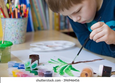 Portrait Of Little School Boy Sitting At The Table And Drawing Palm Tree. After School Activities At Home. Education. Small Boy Creating Handmade Cards.