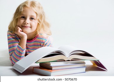 Porträt eines kleinen Schulmädchens, das von hinter Büchern auf weißem Hintergrund lächelt