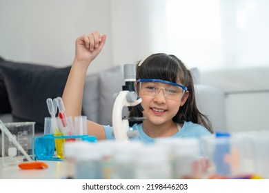 Portrait Of Little Scientist In Protective Glasses Playing With Microscope In Living Room 