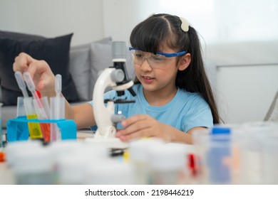 Portrait Of Little Scientist In Protective Glasses Playing With Microscope In Living Room 