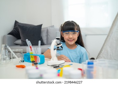 Portrait Of Little Scientist In Protective Glasses Playing With Microscope In Living Room 