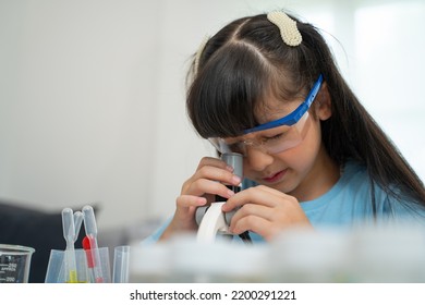 Portrait Of Little Scientist In Protective Glasses Playing With Microscope In Living Room 