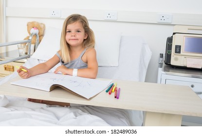 Portrait of little sick girl coloring book while sitting on hospital bed - Powered by Shutterstock