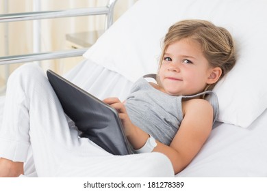 Portrait of little sick girl with digital tablet lying in hospital bed - Powered by Shutterstock