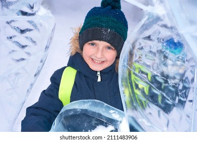 Portrait Of A Little Smiling Boy Looking Through An Ice Fortress In Winter