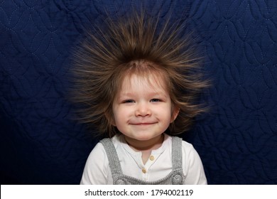 
Portrait of a little smiling girl with electrified hair on a blue background.
Electricity power concept.