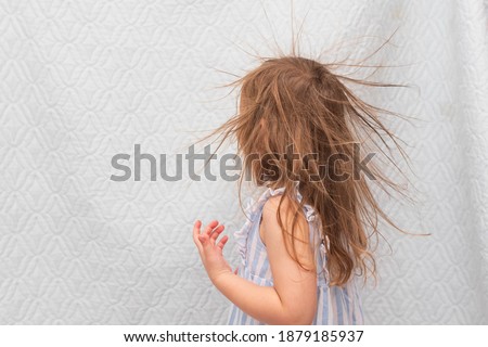 
Portrait of a little smiling girl with electrified hair on a white background.
Electricity power concept.