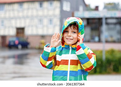 Portrait of little toddler boy playing on rainy day. Happy positive child having fun with catching rain drops. Kid with rain clothes. Children and family outdoor activity on bad weather day.