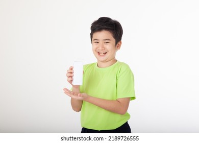 Portrait Of A Little Young Handsome Kid Boy In Green Shirt, Hold Drinking Milk Box Mockup, Isolated On White Background. Concept Of Happy Good Nutrition