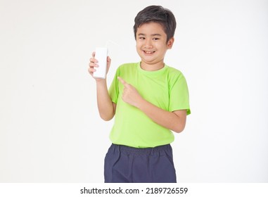 Portrait Of A Little Young Handsome Kid Boy In Green Shirt, Hold Drinking Milk Box Mockup, Isolated On White Background. Concept Of Happy Good Nutrition