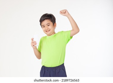 Portrait Of A Little Young Handsome Kid Boy In Green Shirt, Hold Drinking Milk Box Mockup, Isolated On White Background. Concept Of Happy Good Nutrition