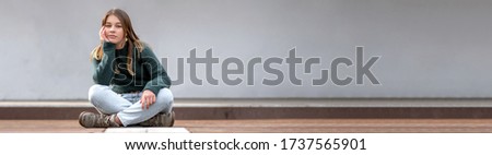 Portrait of a lonely sitting beautiful young teenage girl. Panoramic image