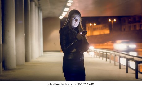 Portrait Of Lonely Woman Typing Text Message On The Dark Street