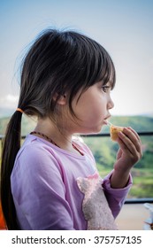 A Portrait Of Long Hair Pretty Little Girl Eating Crispy Spring Roll With Blurry Mountain And Sky Background