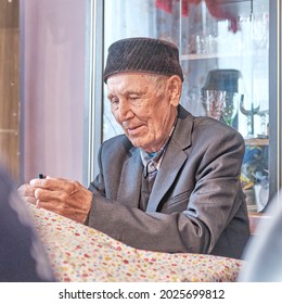 Portrait Of Lost In Thought Asian Senior Muslim Man Sitting At Table At Home