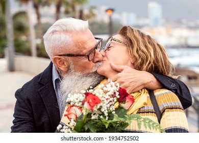 Portrait of lovely attractive cheerful couple of seniors hugging and kissing during the anniversary date. Handsome man surprised his wife with flowers on valentine's day. Real people emotions. - Powered by Shutterstock