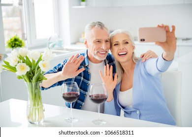 Portrait of lovely attractive stylish cheerful couple drinking red wine alcohol, shooting selfie on front camera, using smart phone, embracing, hugging, gesturing hello symbol, sign with palm - Powered by Shutterstock