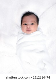 Portrait Of Lovely Baby Girl On Fleece Blanket, Swaddled White Cloth, 2 Weeks Old