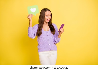 Retrato de una encantadora niña alegre sosteniendo en una tarjeta de papel de mano como usar un dispositivo divirtiéndose aislado sobre fondo de color amarillo brillante