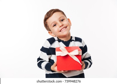 Portrait of a lovely cute little kid holding present box and looking at camera isolated over white background