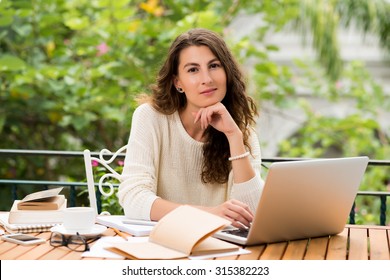 Portrait Of Lovely Female Freelance Writer With A Notebook Sitting At Her Table