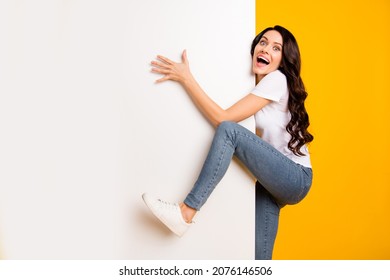 Portrait of lovely funny cheerful wavy-haired girl holding climbing big board copy space isolated on bright yellow color background