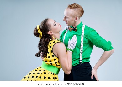 Portrait lovely funny dancer couple dressed in boogie-woogie rock'n'roll pin up style posing together in studio. Woman in yellow polka dots dress and man in green shirt. 