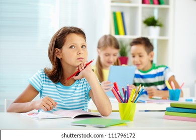 Portrait of lovely girl concentrating on drawing at workplace with schoolmates on background - Powered by Shutterstock