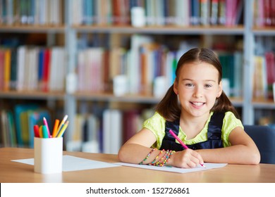 Portrait of a lovely girl drawing with pencil in library - Powered by Shutterstock