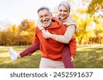 Portrait of lovely happy elderly couple on morning run outside in city park, retirees wife and husband rejoice in active lifestyle, smiling woman tenderly embracing her spouse after routine jogging