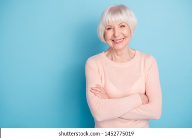 Portrait of lovely lady with her arms folded having toothy smile wearing pastel sweater isolated over blue background