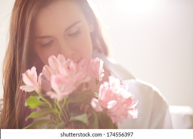 Portrait of lovely lady looking at flowers and smelling them
