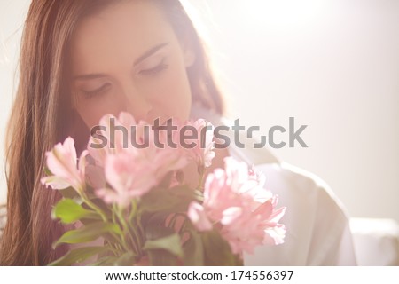 Portrait of lovely lady looking at flowers and smelling them