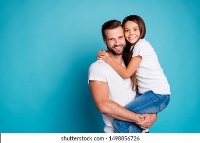 Portrait Of Lovely Man With Brunet Hair Cut Holding His Daughter Having Long Hair Wearing White Casual T-shirt Denim Jeans Isolated Over Blue Background