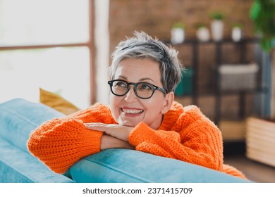 Portrait of lovely positive person sitting cozy sofa toothy smile daydreaming imagine apartment inside - Powered by Shutterstock