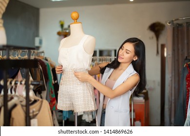 Portrait Of A Lovely Shop Owner Standing Near The Rack Of Clothes Hangings On The Foreground