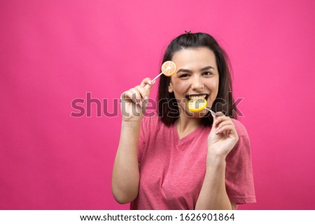 Portrait of lovely sweet beautiful cheerful woman with straight brown hair holding a lollipop near the eyes.