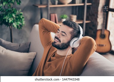 Portrait of lovely sweet man touch head hand close eyes feel rejoice funny funky orange sweater pullover imagine soundtrack sound track sit divan comfy apartment - Powered by Shutterstock