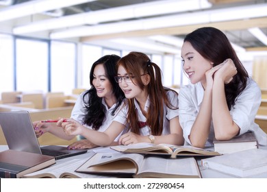 Portrait of lovely three female high school student, studying together in the classroom