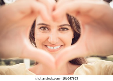 Portrait of a lovely woman making heart of fingers